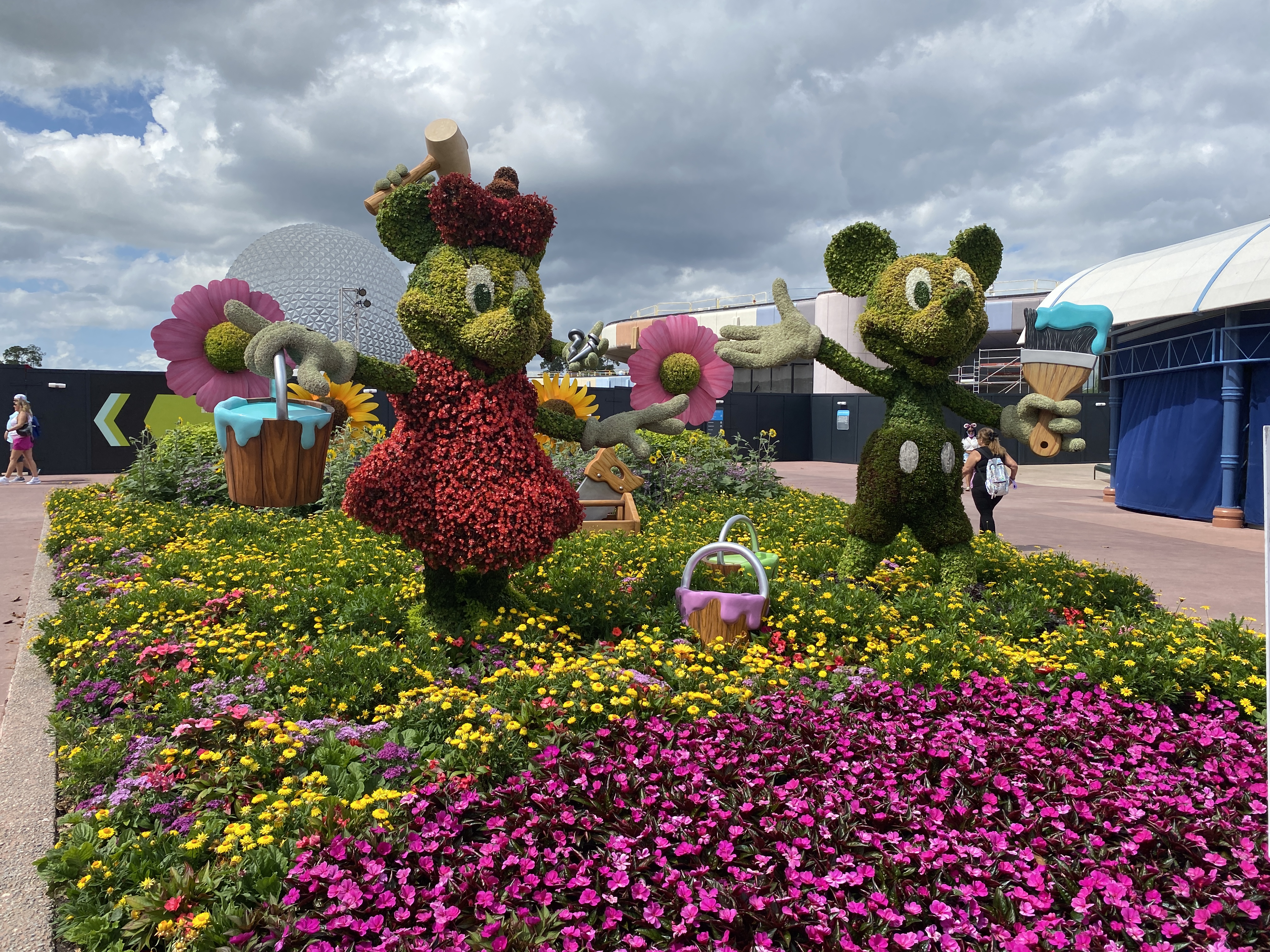 Mickey and Minnie Mouse topiaries surrounded by vibrant yellow, pink, and purple flowers at EPCOT Flower and Garden Festival.